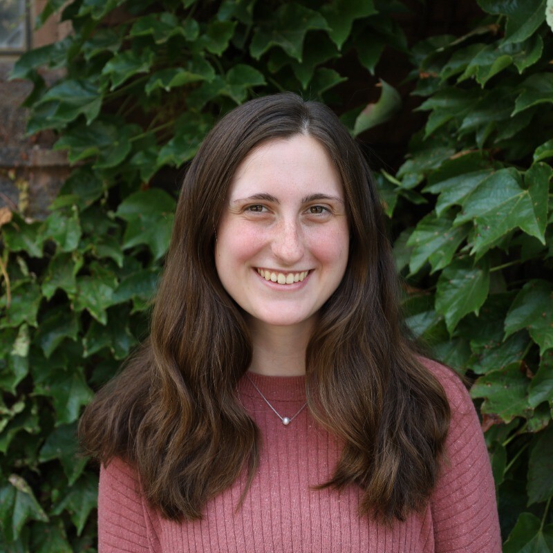 Molly smiling in front of some greenery